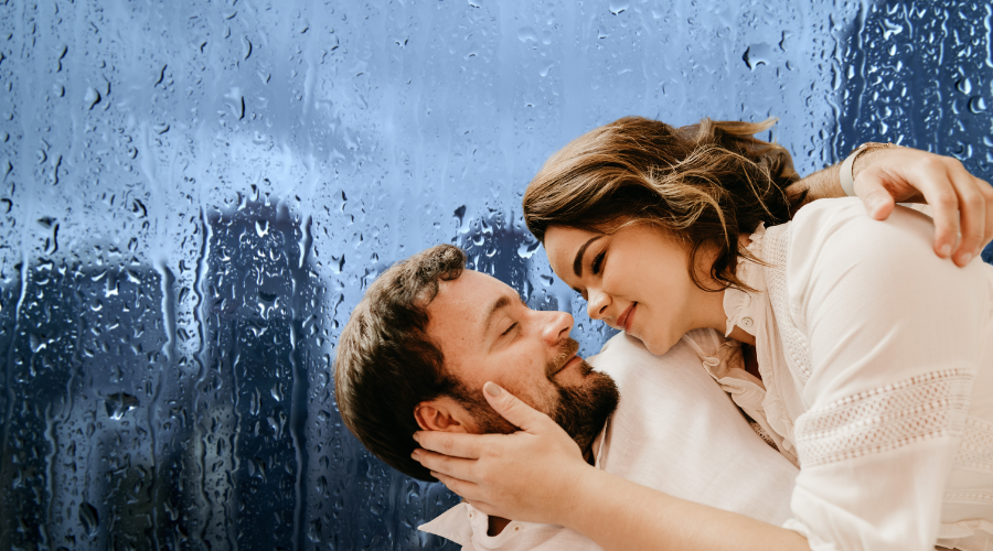 A couple sharing a loving moment in front of a rain-streaked window.